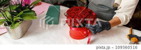 Close up of florist in flower shop make roses compositions for holiday. Family flower's business 109360516