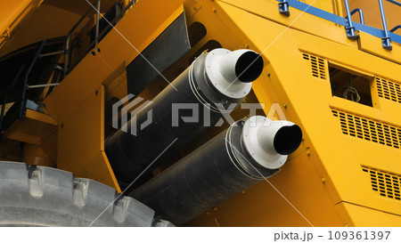 Close-up of two exhaust pipes of a dump truck. Exhaust system of the world's largest dump truck. Yellow huge lorry. Close-up of two exhaust pipes of a dump truck. Exhaust system of the world's largest dump truck. Yellow huge lorry. 109361397