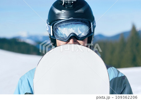 Snowboarder with action camera on a helmet. Close up Portrait of snowboarder in Carpathian Mountains, Bukovel Snowboarder. A mountain range reflected in the ski mask. wearing ski glasses 109362206
