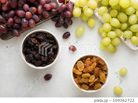 Sweet dried green and red dark raisins with ripe raw grapes on light background.Top view. 109362722