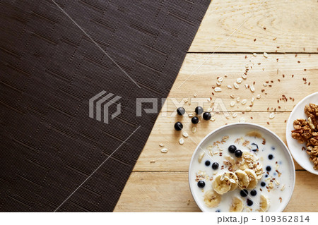 Oatmeal porridge with banana, walnuts and honey in bowl on  wooden background. Healthy breakfast. 109362814