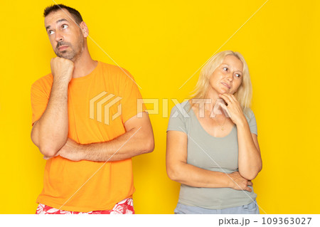 Contemplation of two lovers caucasian 40s couple spouses wife and husband boyfriend and girlfriend looking upwards, planning for future, thoughtful and pensive people isolated in yellow 109363027