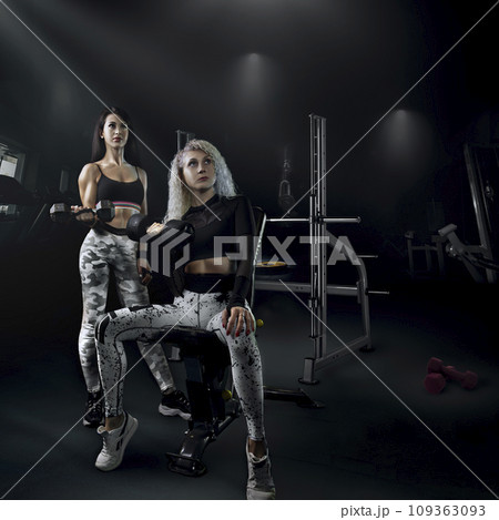 fitness bodybuilding a couple of beautiful girls do sports together with a trainer with a beautiful body and a slim figure pose in the gym, creative photo. High quality photo 109363093