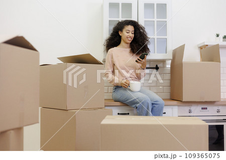 moving to new apartment relocation. happy young woman, packing boxes with personal belongings, 109365075