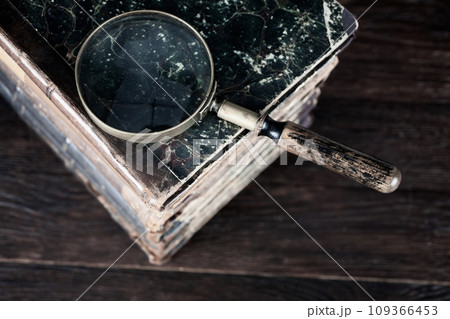 Vintage magnifying glass with books on table Vintage magnifying glass with books on table 109366453