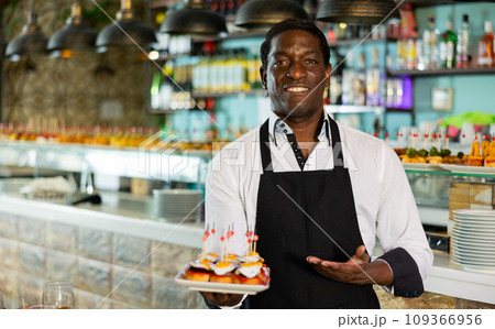 Professional african american waiter holding serving tray for restaurant guests 109366956
