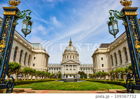 City hall with green courtyard framed by golden gilded lampposts with cloudy blue sky City hall with green courtyard framed by golden gilded lampposts with cloudy blue sky 109367732