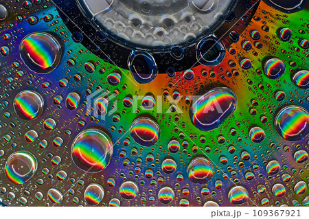 Rainbow burst inside fizzy bubbles floating across colorful metallic surface 109367921