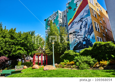 Zen park with building mural of white flowers and mountain view of bonsai trees in the clouds 109368054