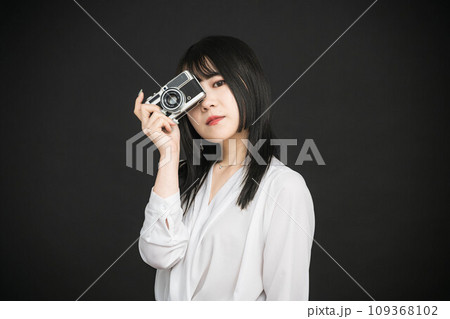 黒バックでカメラを持っている若い女性 109368102