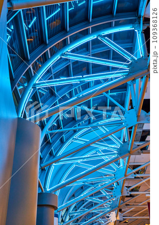 Fierce electric blue neon lighting across curved windows with white ceiling support beams Fierce electric blue neon lighting across curved windows with white ceiling support beams 109368126