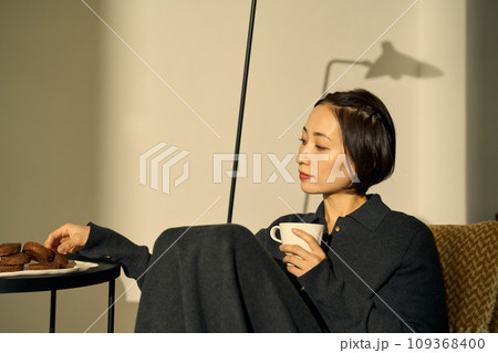 夕暮れ時、ソファーでくつろぐ女性 109368400