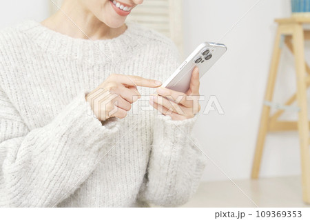 リビングでスマートフォンを使う女性 顔無し リビングでスマートフォンを使う女性 顔無し 109369353