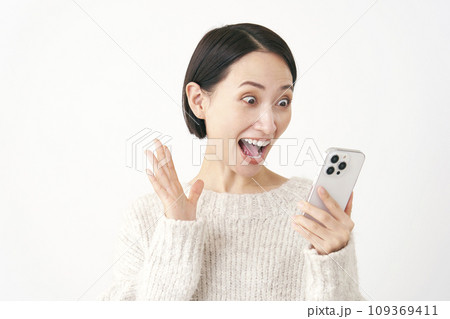 スマホを見て笑顔で驚くミドルエイジの女性 白背景 スマホを見て笑顔で驚くミドルエイジの女性 白背景 109369411