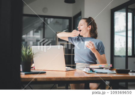 Bored businesswoman yawning at workplace feeling no motivation or lack of sleep tired of boring office routine. Bored businesswoman yawning at workplace feeling no motivation or lack of sleep tired of boring office routine. 109369650
