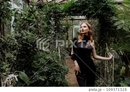 A woman walking through a greenhouse. 109371328