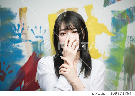 カラフルな壁の前に立ち手を組む若い女性 109371764