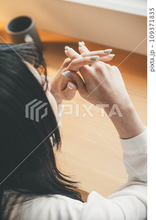 窓際のテーブルに座っている女性の手元 109371835