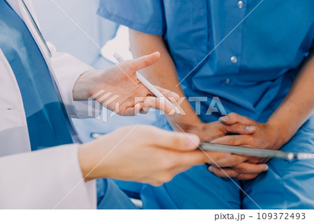 Side view of diverse doctors examining Asian female patient in bed in ward at hospital. 109372493