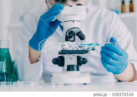biochemical research scientist team working with microscope for coronavirus vaccine development in pharmaceutical research labolatory, selective focus 109372516