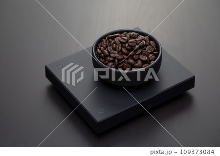 Roasted coffee beans on a black digital scale. 109373084