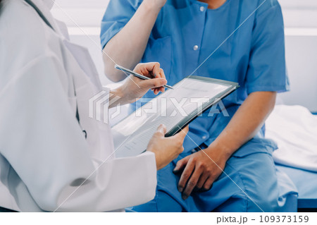 Doctor telling to patient woman the results of her medical tests. Doctor showing medical records to cancer patient in hospital ward. Senior doctor explaint the side effects of the intervention. Doctor telling to patient woman the results of her medical tests. Doctor showing medical records to cancer patient in hospital ward. Senior doctor explaint the side effects of the intervention. 109373159
