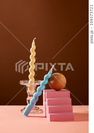 Two twisted candles are displayed with some props on the table. Brown background. Exquisite space for product display, magazine posting or other purposes. 109373721