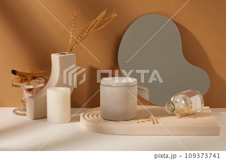 Unbranded scented candles in a jar rest on a domed podium, acrylic sheet, and adorned backdrop of white and brown. Elegant and refined space. Copy space for ads. Unbranded scented candles in a jar rest on a domed podium, acrylic sheet, and adorned backdrop of white and brown. Elegant and refined space. Copy space for ads. 109373741