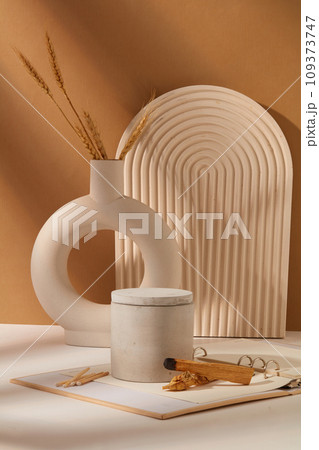 A jar of scented candles is displayed on a table with props. White-brown background. Mockup for advertising. Scented candles help eliminate unpleasant odors in the room. A jar of scented candles is displayed on a table with props. White-brown background. Mockup for advertising. Scented candles help eliminate unpleasant odors in the room. 109373747
