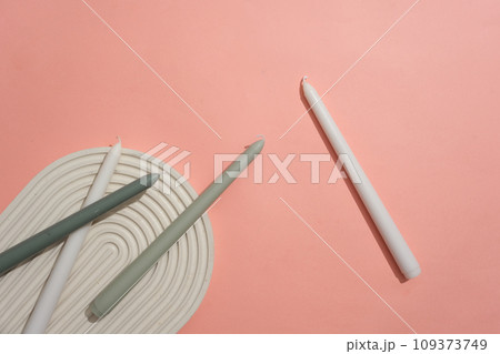 White and gray candles are displayed on a pink background with a domed podium. Empty space for product display. Creative space for advertising and more. White and gray candles are displayed on a pink background with a domed podium. Empty space for product display. Creative space for advertising and more. 109373749