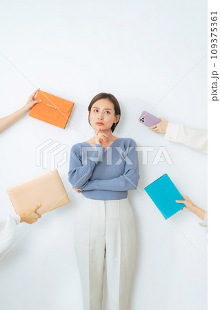 デジタルデバイスやノートを差し出されて悩む女性 109375361