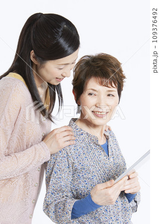 タブレットを操作する祖母と娘 109376492