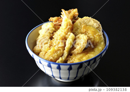 海老、ちくわ、インゲン、カボチャ、さつま芋、蓮根が乗っている具だくさんの天丼を黒背景で撮影 109382138