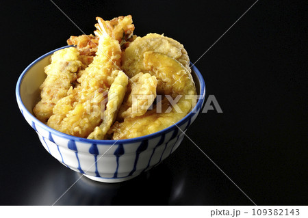 海老、ちくわ、インゲン、カボチャ、さつま芋、蓮根が乗っている具だくさんの天丼を黒背景で撮影 109382143