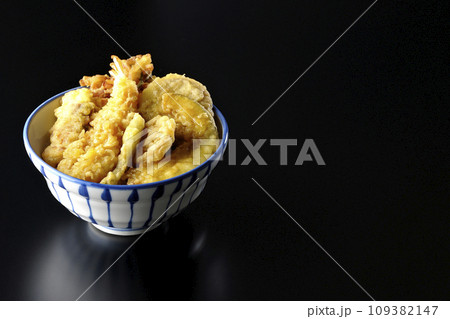 海老、ちくわ、インゲン、カボチャ、さつま芋、蓮根が乗っている具だくさんの天丼を黒背景で撮影 109382147