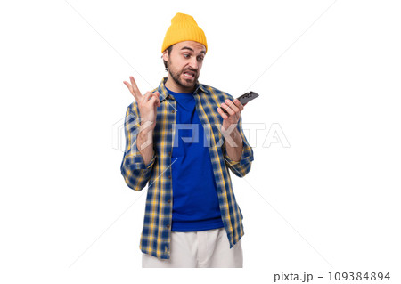 young stylish brunette man with a beard and mustache in a shirt and hat writes a voice message 109384894