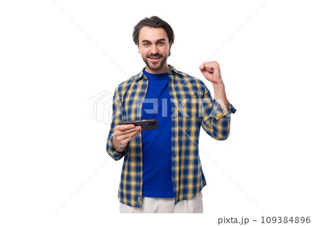 a young caucasian brutal man with an unshaven face dressed in a blue plaid shirt is watching a video a young caucasian brutal man with an unshaven face dressed in a blue plaid shirt is watching a video 109384896