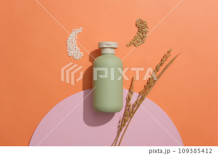 Empty label bottle in pastel green color displayed with handful of rice and wheat seeds. Flat lay. Mockup of skin care cosmetic bottle of beauty facial Empty label bottle in pastel green color displayed with handful of rice and wheat seeds. Flat lay. Mockup of skin care cosmetic bottle of beauty facial 109385412