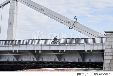 Man riding on bicycle across the bridge in the city. 109385967