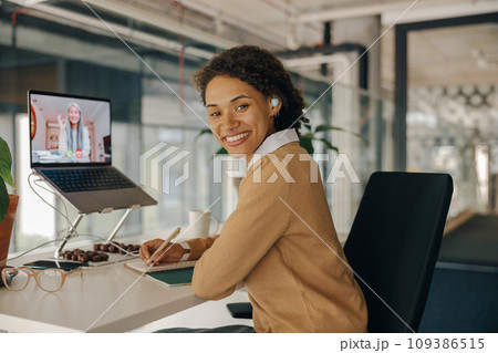 Female freelancer have video conference with client and making notes sitting in cozy coworking 109386515