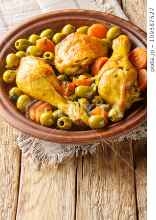 Tajine Zitoune is an Algerian stew dish that consists of chicken cooked with carrots and green olives using north African spices close-up. Vertical 109387527