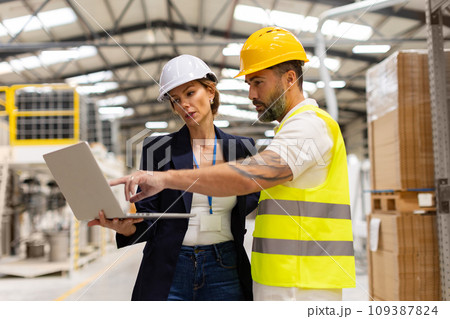 Female manager talking with foreman, checking production plan on notebook. Woman quality controller checking quality of products, talking with technician. Female manager talking with foreman, checking production plan on notebook. Woman quality controller checking quality of products, talking with technician. 109387824