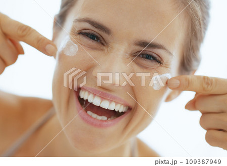 Happy young woman having fun time while applying cream in bathro Happy young woman having fun time while applying cream in bathro 109387949