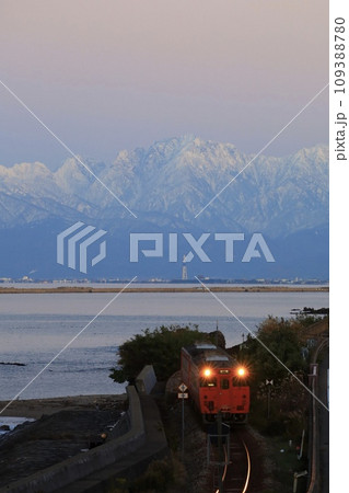 立山連峰をバックに走る電車 109388780