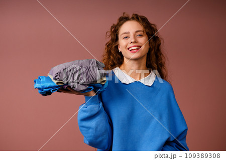 Young positive smiling woman holds in her hands a stack of winter clothes Young positive smiling woman holds in her hands a stack of winter clothes 109389308