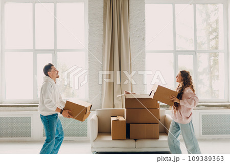 Happy young family couple man and woman holds cardboard boxes on new home. Moving delivery concept. 109389363