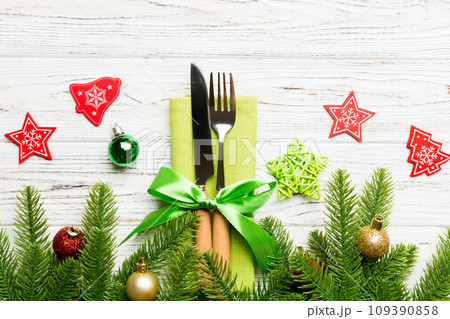 Top view of christmas decorations on wooden background. Fork and knife on napkin tied up with ribbon and empty space for your design. New year pattern concept 109390858