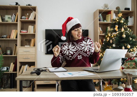 Successful woman in Santa hat and warm winter clothes dancing with excitement 109391057