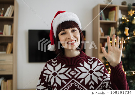 Female waving hello while posing to webcam while greeting colleague or family Female waving hello while posing to webcam while greeting colleague or family 109391734