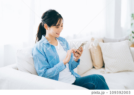 ソファに座ってスマホを見る女性 ソファに座ってスマホを見る女性 109392003
